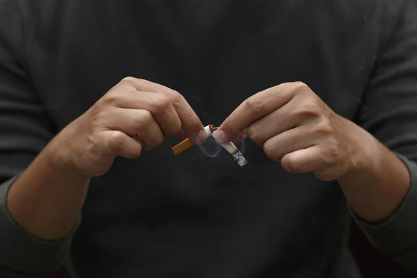 Man holding broken cigarette in hands. Stop smoking cigarettes concept. No smoking campaign concept.